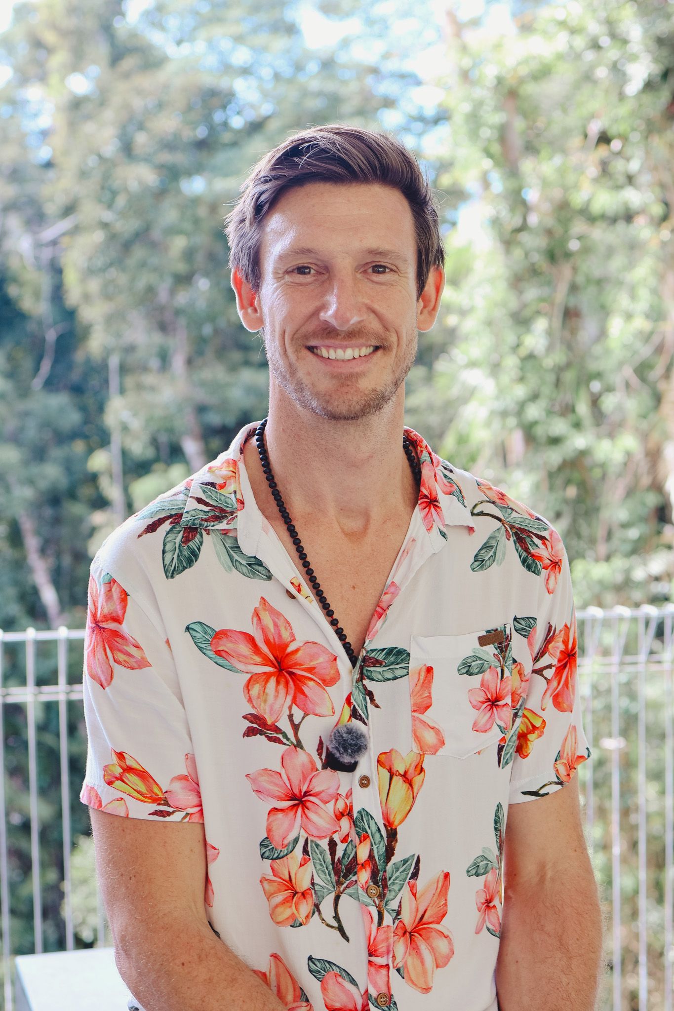 Mat Bankes in a floral shirt, smiling, with rainforest behind him at Connect Fest, Cairns